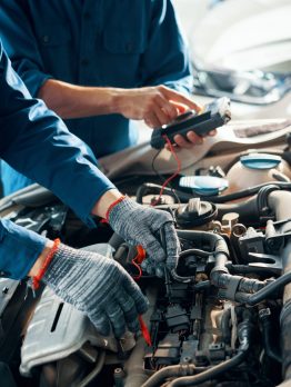 Hands of professional mechanics using professional tool for testing car motor in garage